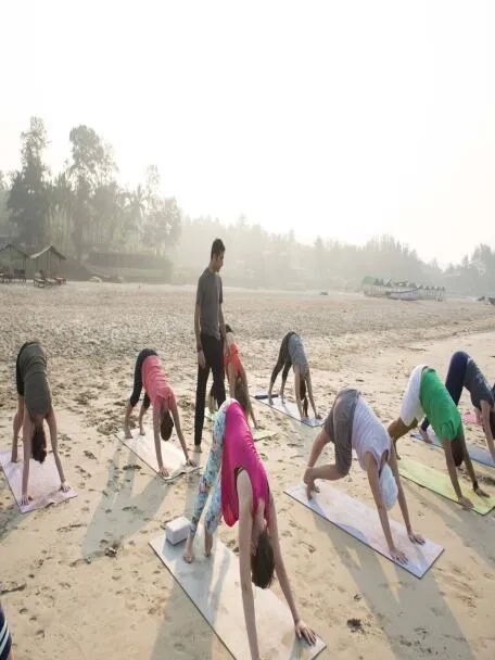 A group of people doing yoga on a sandy beach with an instructor.