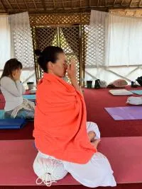 A woman in an orange shawl meditating in a group