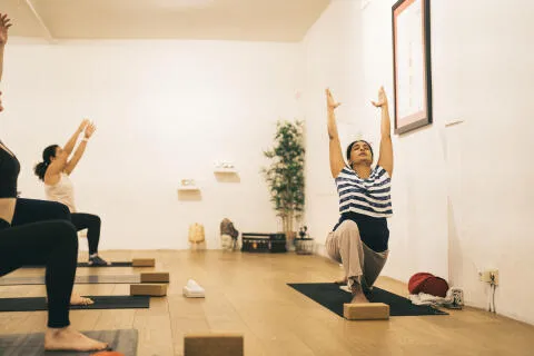 Yoga teacher and students practicing low lunge